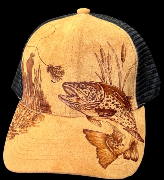 Fly fishing trout scene, hand-burned using a wood burner. Faux suede ball cap. Free custom wording on brim if requested. Wearable art!