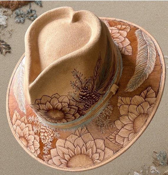 Heart top, one of a kind free-hand, hand-burned floral pine design. Size medium hard body wide brim with sloped front and back. Camel tan.