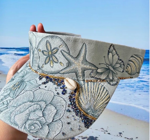 Nautical garden theme.  Vegan (faux) suede light blue visor.  Gold and blue “sand”, beads, and gold acrylic paint.