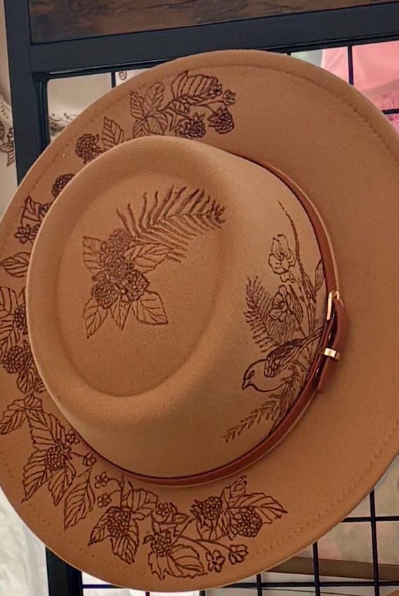 Hand burned, fedora in camel color felt. Gorgeous detailed blackberries, ferns, and finch.Inspired by childhood berry picking. Wearable art.