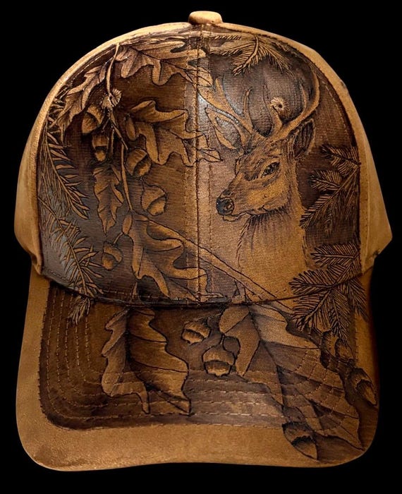 Buck in the woods, free-hand, hand-burned using a hand held wood burner. Vegan (faux) suede tan with adjustable slide back.