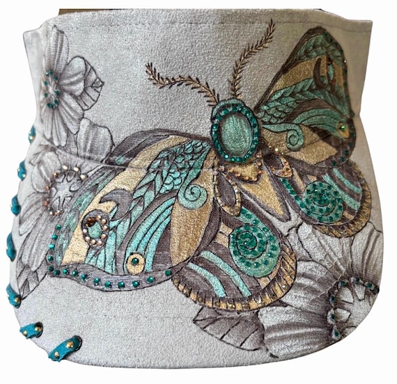 Free-hand, hand burned moth and floral design. Vegan (faux) suede light grey visor.  Teal and bronze permanent acrylic paint, & rhinestones.