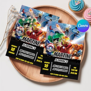 May include: Two party invitations featuring superhero characters, with the name "MARTINE" and the text "IS TURNING 5". The invitations include event details and are placed on a wooden tray with cupcakes.