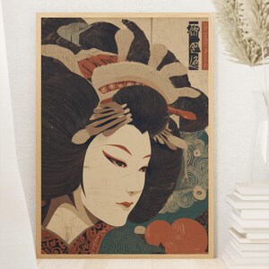 以下が含まれることがあります： 日本の芸者の額入りプリント。このアートワークは、肌が白く、唇が赤く、髪が黒い女性を特徴としています。背景には、ティール、オレンジ、ベージュのパターンが含まれています。プリントは木製のフレームに入っています。