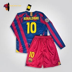 Könnte beinhalten: Ein blau-rotes Fußballtrikot- und Shorts-Set. Das Trikot hat lange Ärmel mit roten und blauen Streifen, den Namen "RONALDINHO" und die Nummer "10" in Gelb. Die Shorts sind rot mit der Nummer "10" und einem Teamlogo.