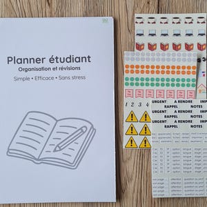 Peut inclure: Un agenda étudiant à spirales blanches avec le texte "Planner étudiant" et "Organisation et révisions". Comprend des feuilles d'autocollants avec des icônes, des étiquettes et une variété de points colorés. L'agenda a un dessin d'un livre ouvert et d'un crayon.