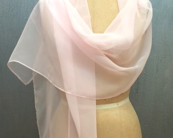 May include: A pale pink scarf draped over a vintage dress form. The scarf is made of a sheer, lightweight fabric, with a soft, flowing appearance. The dress form is a neutral beige colour, with visible markings.