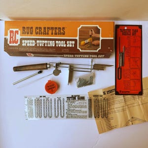 May include: A Rug Crafters speed-tufting tool set including a metal tufting tool with a wooden handle, a needle threader, a small orange container of lubricant, a packet of metal pins, a tufting gauge, a tapestry yarn needle set, and instructions.