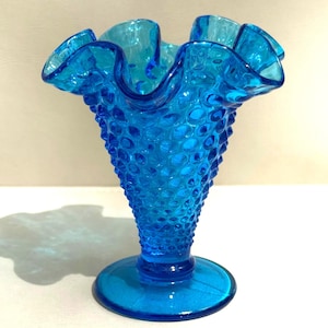 May include: A set of three ceramic mugs with a speckled, matte finish. The mugs are in shades of cream, light gray, and dark gray. Each mug has a simple, minimalist design and a rounded handle.