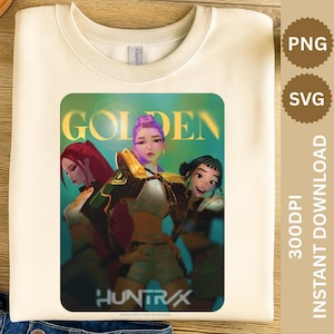 Puede incluir: Sudadera de color crema con un gráfico colorido de tres figuras femeninas estilizadas y la palabra "GOLDEN" encima. El gráfico también incluye el texto "HUNTR/X" en la parte inferior. La sudadera está doblada sobre una superficie de mezclilla azul.