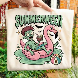 May include: A beige tote bag with a cartoon zombie on a pink flamingo float. The zombie is holding a coconut drink. The word "SUMMERWEEN" is printed above the zombie in green, with bats and stars.