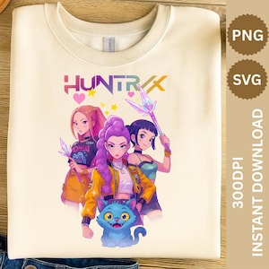 May include: Cream-colored sweatshirt featuring a colorful graphic of three anime-style characters and a blue cat. The word "HUNTRAX" is displayed in a vibrant font above the characters. The design includes hearts, stars, and crystal-like weapons.
