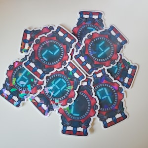 Puede incluir: Una colección de pegatinas con un diseño de reloj digital. Los relojes tienen un marco rojo y negro con una pantalla digital azul que muestra números. Algunas pegatinas tienen un acabado holográfico iridiscente.