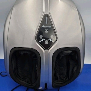 May include: A silver electric foot massager with a black control panel featuring the brand name Allyouger. The device includes two foot chambers lined with black fabric and a central interface with buttons for power, heat, mode, and intensity.