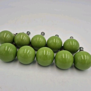 May include: A collection of ten spherical cabinet knobs with a smooth, glossy olive green finish. Each knob features a rounded ceramic head and a short, silver-toned metal bolt extending from the back for attachment to furniture or cabinetry.