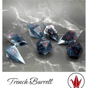 May include: Seven polyhedral dice with a marbled blue and white design and red numbering. The dice are displayed on a grey, marbled surface. The text "Trench Barrell" is at the bottom of the image.