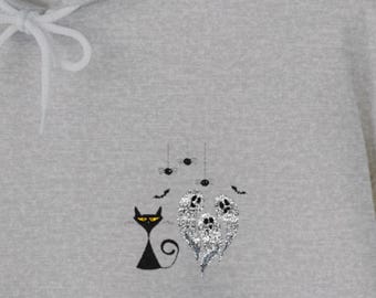 Puede incluir: Una sudadera con capucha gris claro con un diseño temático de Halloween. El diseño incluye un gato negro con ojos amarillos, tres fantasmas de purpurina plateada, arañas y murciélagos. La sudadera tiene un cordón y un bolsillo delantero.