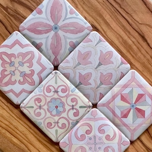May include: A set of five square ceramic tiles arranged in a diamond orientation, each featuring a unique pattern in shades of soft pink, light blue, and cream. The designs include floral motifs, geometric shapes, and intricate scrollwork patterns.