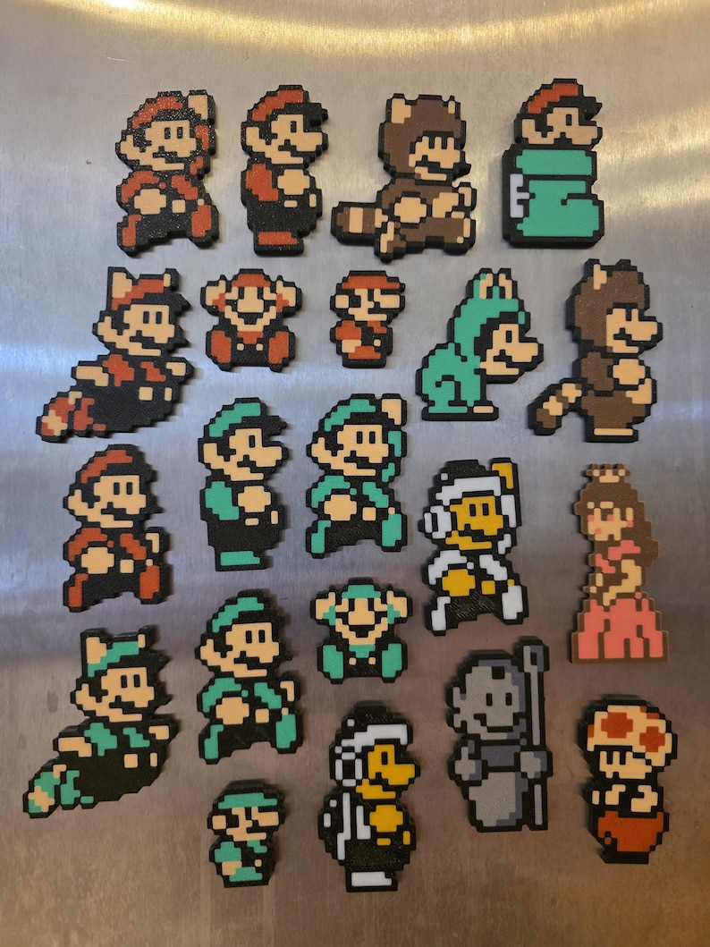 Puede incluir: Una colecci&oacute;n de imanes de pixel art con personajes de la serie de videojuegos Super Mario. Los imanes representan a Mario, Luigi, la Princesa Peach y otros personajes en varias poses y disfraces. Los imanes est&aacute;n hechos de cuentas de pl&aacute;stico de colores.