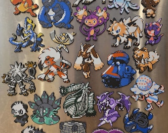 Könnte beinhalten: Eine Sammlung von zweiundzwanzig Pixel-Art-Figuren aus Kunststoff-Bügelperlen, die verschiedene stilisierte Kreaturen darstellen. Die Figuren weisen unterschiedliche Formen und Farbpaletten auf, darunter Blau-, Orange-, Violett-, Weiß- und Grautöne, die in einem gitterartigen Muster auf einer metallischen Oberfläche angeordnet sind.