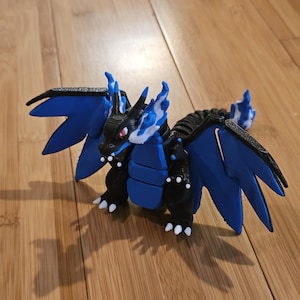 Könnte beinhalten: Eine 3D-gedruckte Drachenfigur in Blau und Schwarz mit weißen Akzenten. Der Drache hat große Flügel und ein detailliertes Design. Ideal für Sammler oder Fans von Fantasy-Kreaturen.