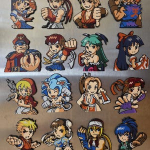 May include: A collection of sixteen pixel art magnets featuring various video game characters in colorful outfits and dynamic poses. Each figure is rendered in a distinct blocky style, showcasing diverse hair colors, costumes, and expressions arranged in a grid.