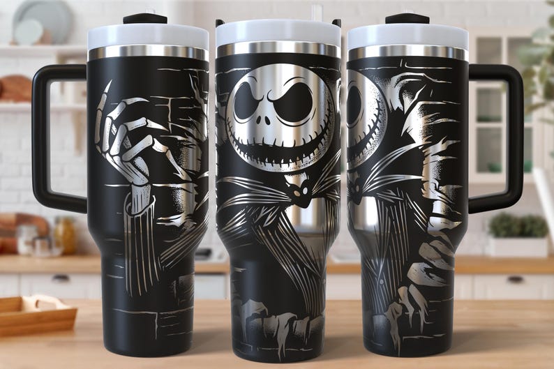 May include: Black travel mugs with a white lid and handle, featuring a silver illustration of Jack Skellington from The Nightmare Before Christmas. The design includes skeletal hands and Jack's face.