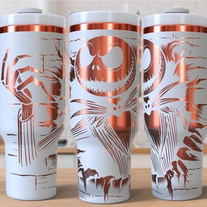 May include: White travel mug with a copper-colored design featuring Jack Skellington from The Nightmare Before Christmas. The mug has a white lid, a copper-colored band, and a gray handle. The design wraps around the mug.