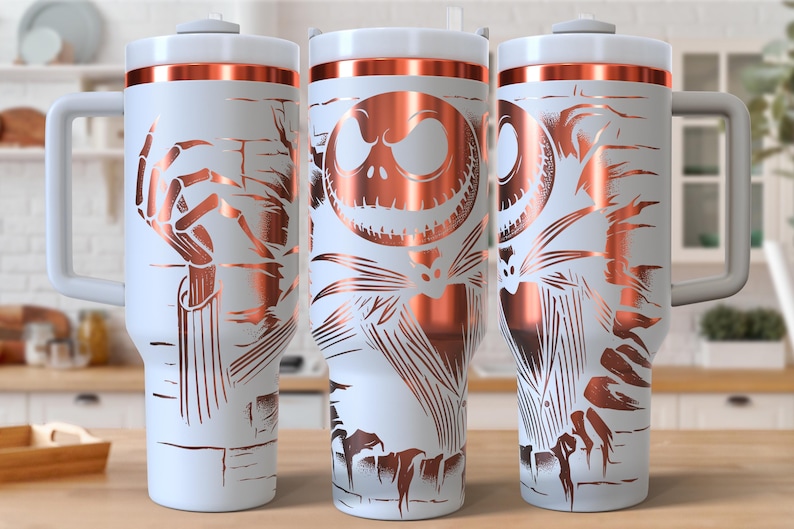 May include: White travel mug with a copper-colored design featuring Jack Skellington from The Nightmare Before Christmas. The mug has a white lid, a copper-colored band, and a gray handle. The design wraps around the mug.