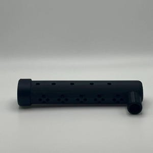 Könnte beinhalten: Ein schwarzes, zylindrisches Objekt mit einer Reihe kleiner, gleichmäßig verteilter Löcher entlang seiner Länge. Es hat ein abgerundetes Ende und einen rechtwinkligen, kleineren zylindrischen Ansatz. Das Objekt besteht aus einem matten Material.