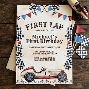 May include: A vintage-style birthday invitation with a race car theme. The invitation features the text "FIRST LAP" and "Michael's First Birthday." A toy race car and checkered flags are also visible. The invitation is on a wooden surface.