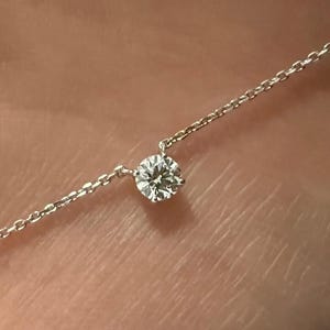 Peut inclure: Un collier &agrave; cha&icirc;ne fine de couleur argent&eacute;e orn&eacute; d'une unique petite pierre pr&eacute;cieuse transparente, ronde et taill&eacute;e en brillant, fix&eacute;e dans un serti &agrave; griffes simple. Le collier se compose de fins maillons circulaires entrelac&eacute;s.