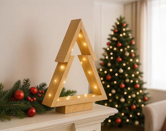 May include: A light-coloured wooden Christmas tree decoration with a geometric, open-frame design. The structure is illuminated by thin, warm-toned string lights wrapped around the frame, creating a soft glow against the natural wood grain.