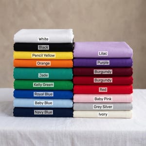 May include: A stack of folded fabric in various colors, including white, black, yellow, orange, green, blue, purple, red, pink, and gray. Each color is labeled with its name, such as "White," "Black," and "Lilac."