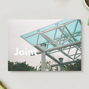 Può includere: Fotografia di una moderna struttura architettonica con un tetto in vetro color verde acqua e travi di supporto bianche. La parola "Joint" è visualizzata in testo bianco. Una tazza di caffè verde si trova nell'angolo in alto a destra.