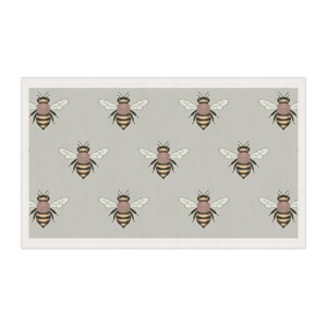 May include: A rectangular decorative item featuring a repeating pattern of bees. Each bee has a brown and yellow body, white wings, and is set against a light gray background. The item is framed with a white border.