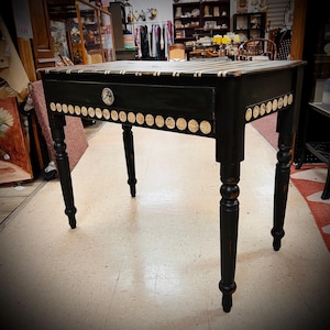 May include: A white ceramic mug with a black handle and the text "But First, Coffee" in a black, bold font. The mug is on a white surface.