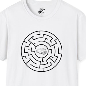 Puede incluir: Camiseta blanca con un diseño de laberinto circular negro y un gráfico de cerebro en el centro. La camiseta tiene mangas cortas y cuello redondo. El logotipo de la marca es visible en la parte superior izquierda.
