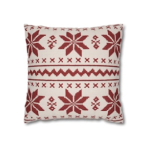 May include: A square throw pillow featuring a cream-colored base with a repeating dark red pattern. The design includes large eight-pointed stars, horizontal rows of small crosses, and a central zigzag line across the middle of the fabric.