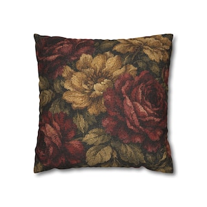 Puede incluir: Cojín cuadrado con un diseño floral. El patrón presenta grandes rosas en tonos burdeos y dorados, sobre un fondo oscuro. La tela del cojín tiene una apariencia texturizada, realzando la estética vintage. Perfecto para la decoración del hogar.