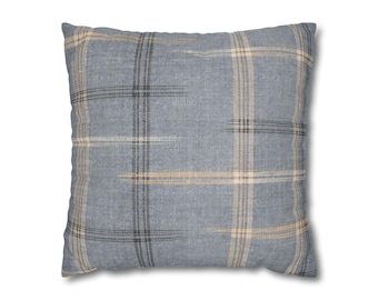May include: Square throw pillow with a blue plaid pattern. The pillow features a grid design with intersecting lines in shades of gray and tan. The pillow is a square shape and appears to be made of a soft fabric.