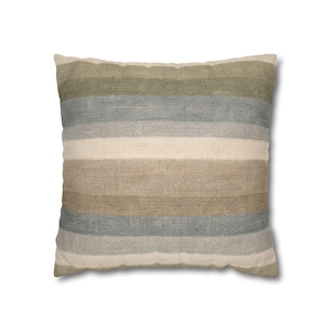 Può includere: Cuscino quadrato con strisce orizzontali beige, verdi e blu. Il tessuto ha un aspetto strutturato, che suggerisce una trama. La palette di colori neutri lo rende adatto a vari stili di interni. Dimensioni: circa 40 cm x 40 cm.