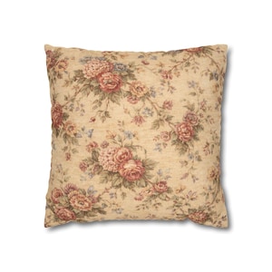 Può includere: Cuscino quadrato con motivo floreale. Il cuscino presenta uno sfondo color crema con un motivo ripetuto di fiori rossi, rosa e blu e foglie verdi. Il cuscino è probabilmente realizzato in tessuto.
