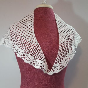 May include: White crocheted collar with a scalloped edge.