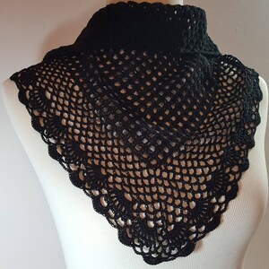 May include: A black crocheted collar with a delicate, lacy design. The collar is made of a fine, open-weave fabric and has a scalloped edge.