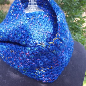 May include: A blue crocheted cowl with colorful flecks throughout. The cowl is folded over and displayed on a black mannequin.