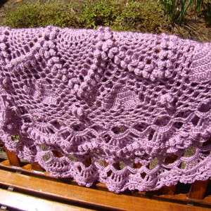 May include: A delicate lavender crocheted shawl with a scalloped edge and intricate floral patterns.