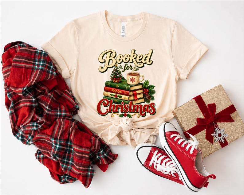 A beige t-shirt with a graphic design of stacked books and a mug, along with a red plaid shirt, a gift box, and a pair of red sneakers.