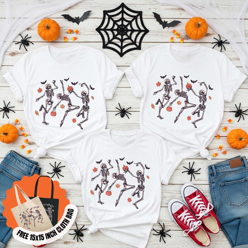 May include: White t-shirts featuring a Halloween skeleton dance design. The image includes pumpkins, bats, spiders, and a tote bag that says "FREE 15x15 INCH CLOTH BAG". Red trainers and blue jeans are also in the image.