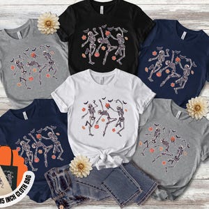 May include: Selection of t-shirts in grey, black, white, and navy blue, each displaying a dancing skeleton design with bats and pumpkins. Includes a free 38x38 cm cloth bag.